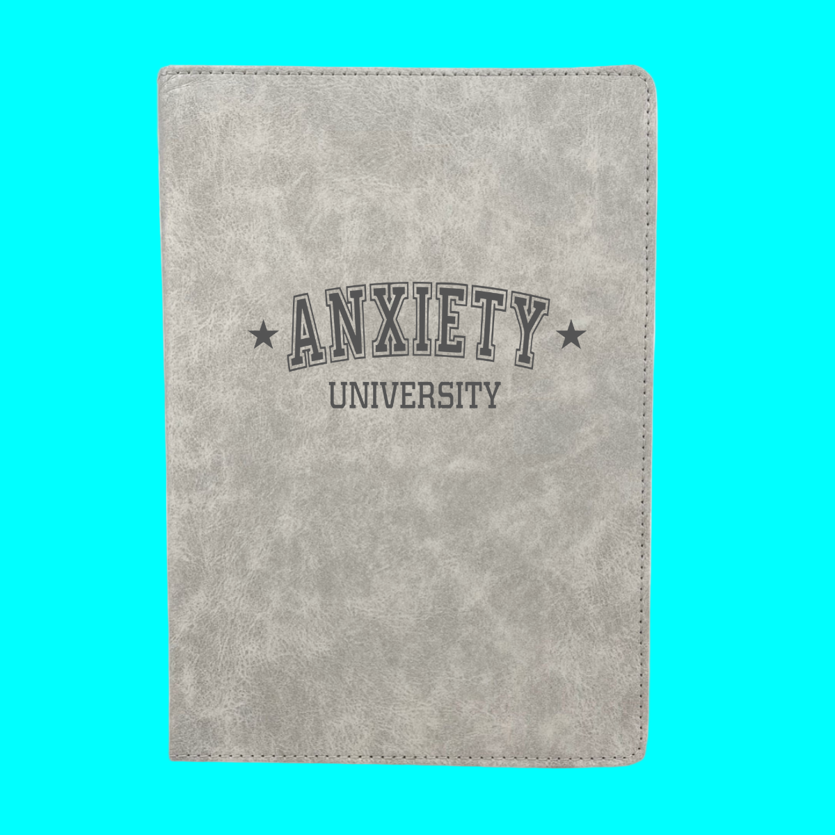 Gray notebook with 'ANXIETY UNIVERSITY' text on a turquoise background