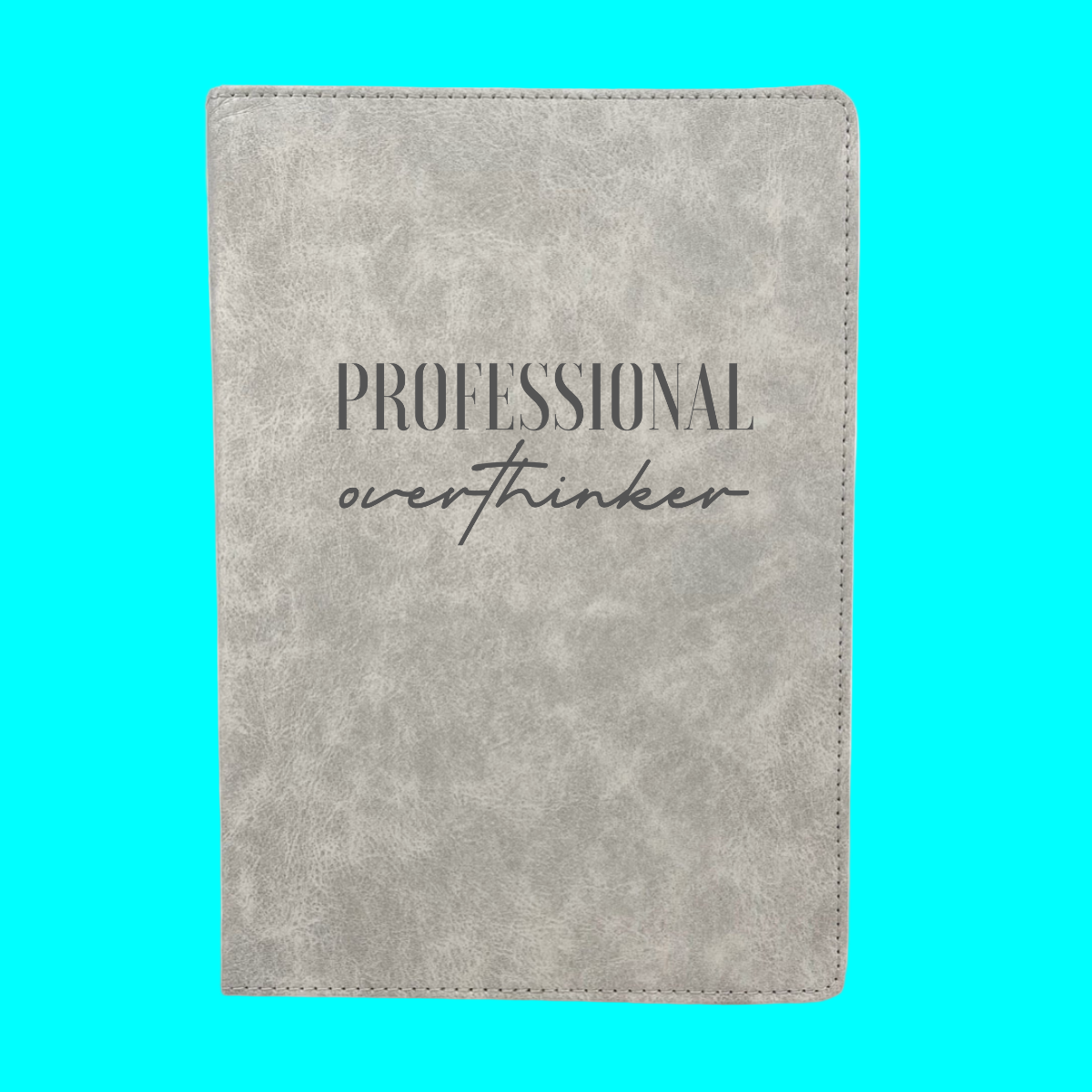 Gray notebook with 'Professional overthinker' text on a turquoise background