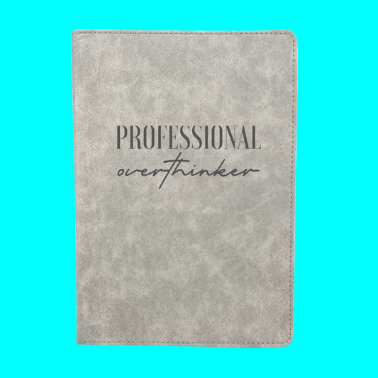 Gray notebook with 'Professional overthinker' text on a turquoise background