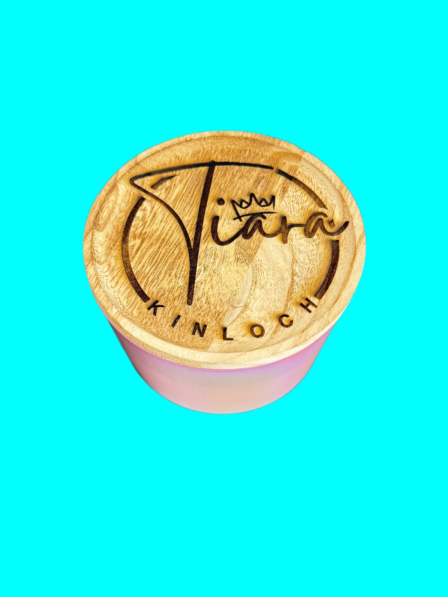 A custom engraved bamboo lid with the name 'Tiara' on it, placed on a candle, with the text 'Kinloch' written below.