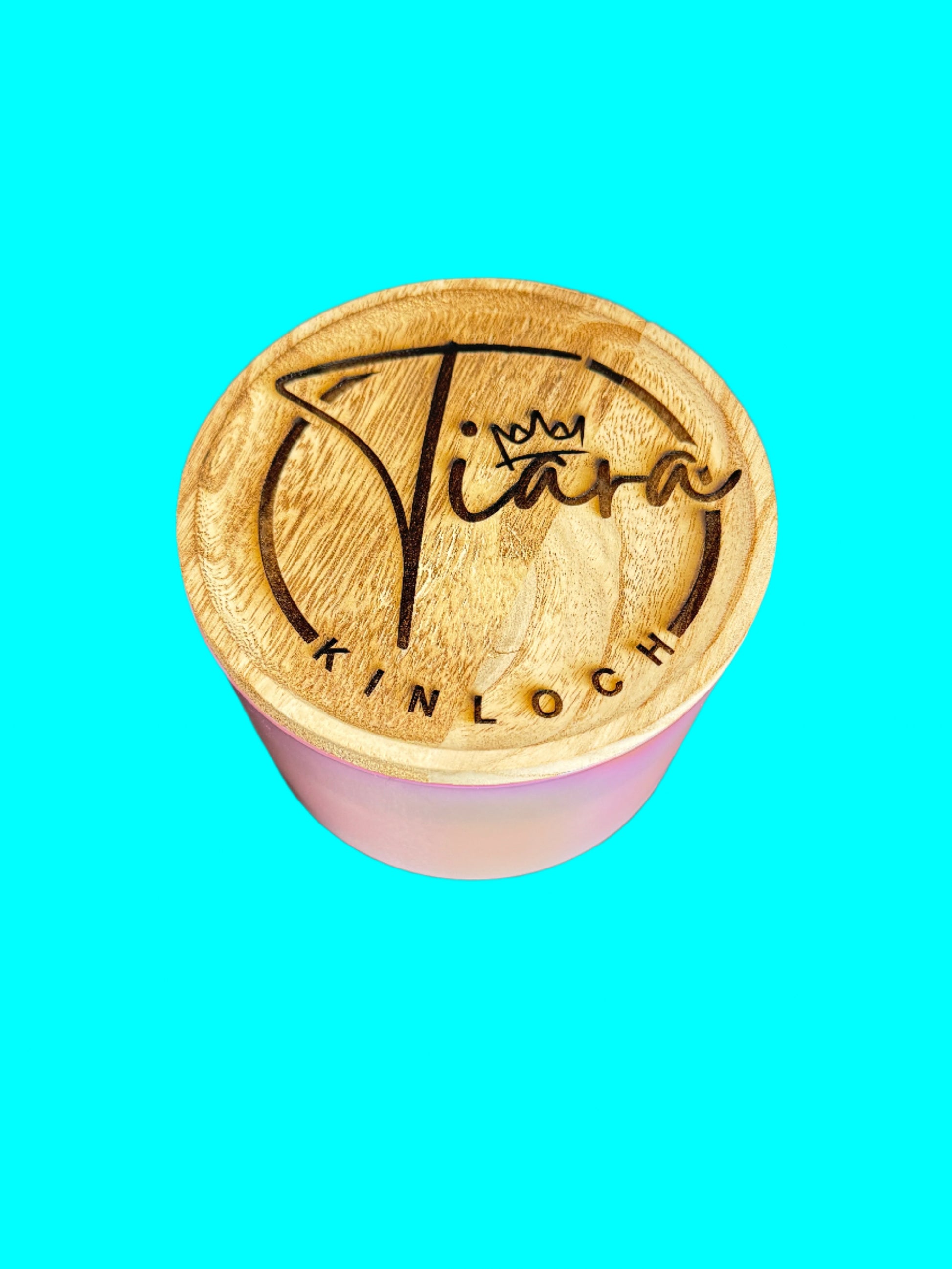 A custom engraved bamboo lid with the name 'Tiara' on it, placed on a candle, with the text 'Kinloch' written below.